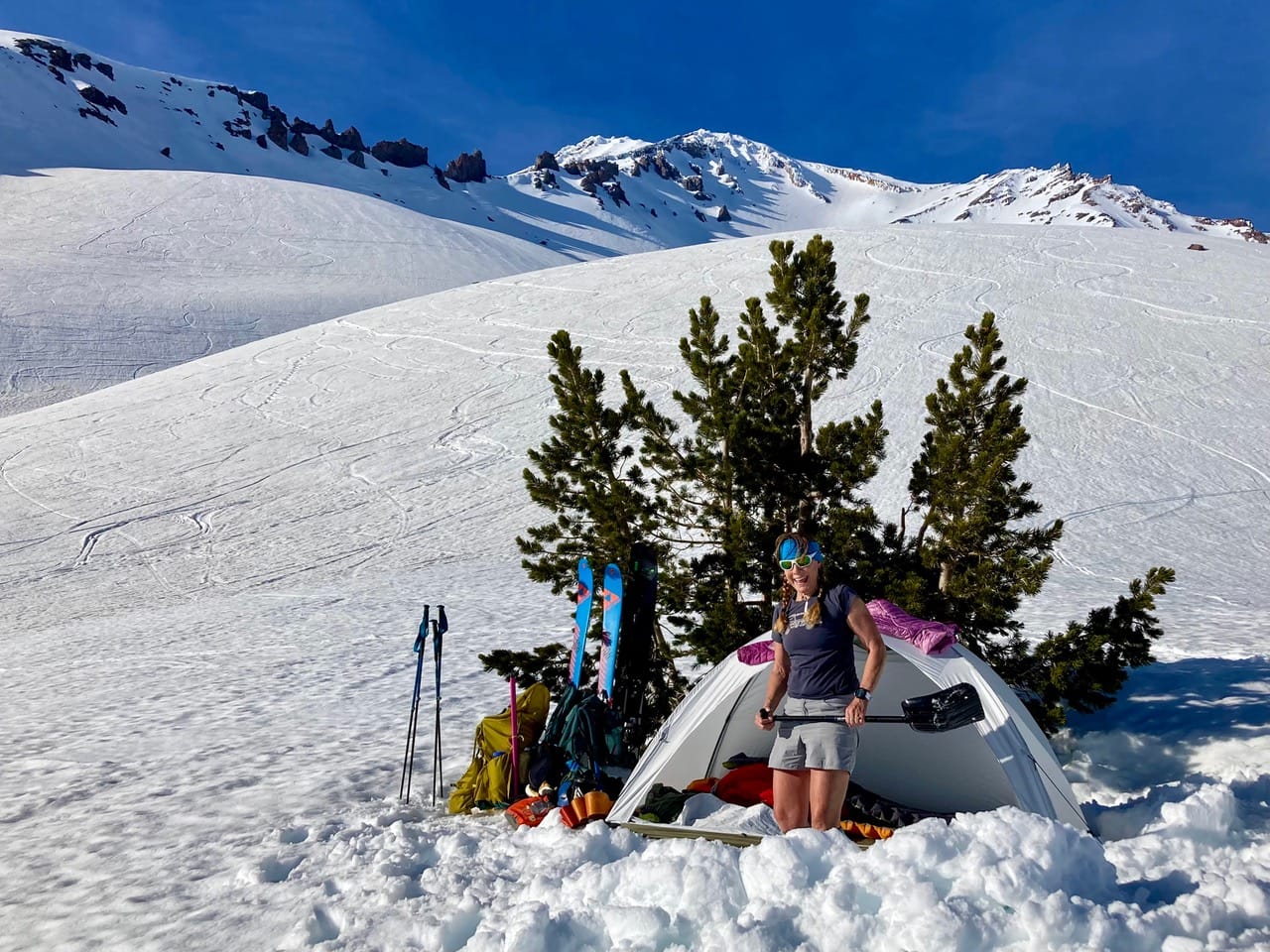 Picture of Becky holding a shovel in front of her tent. 