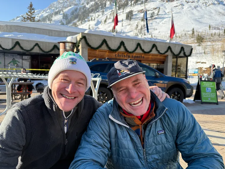 Picture of two guys laughing in front of a ski hill. 